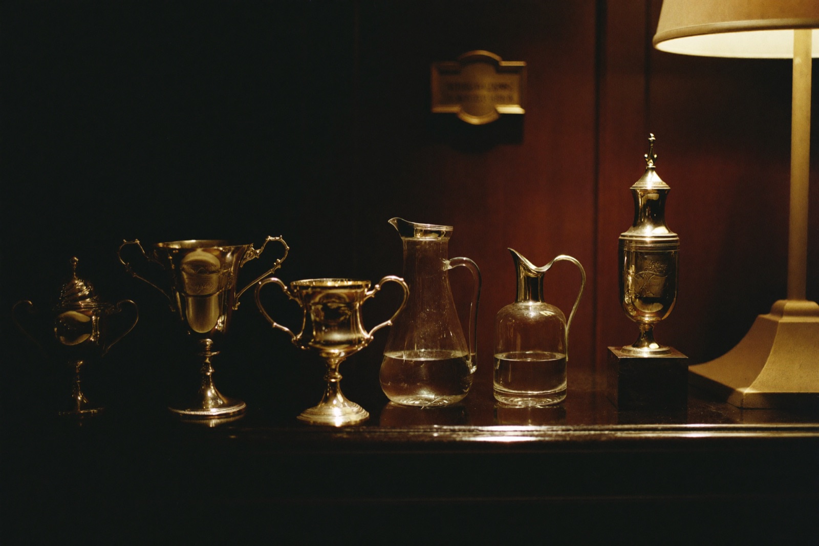 A dark trophy hall with brass plaques and silver cups